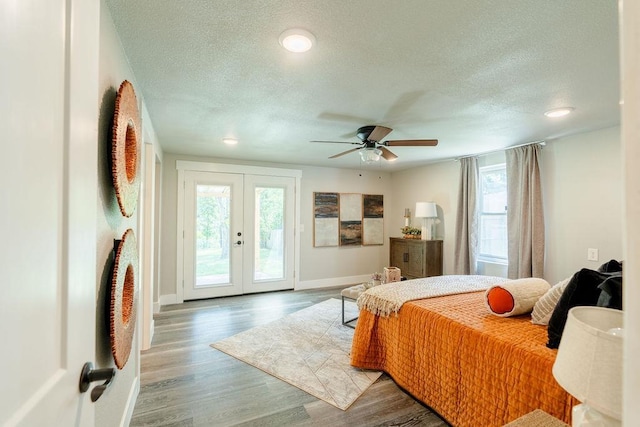 bedroom featuring baseboards, wood finished floors, access to exterior, a textured ceiling, and french doors