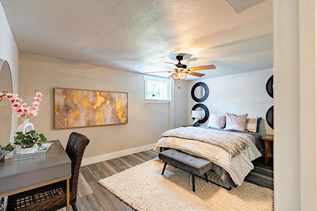 bedroom featuring a ceiling fan, a textured ceiling, baseboards, and wood finished floors