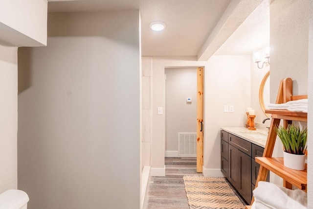 full bath featuring vanity, wood finished floors, visible vents, and baseboards