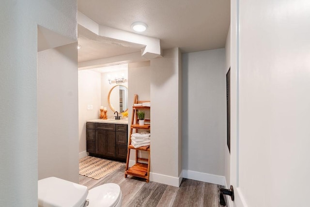 bathroom featuring toilet, wood finished floors, vanity, and baseboards