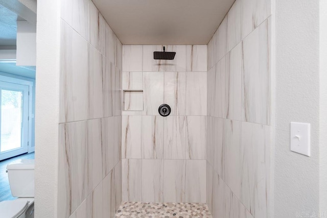 bathroom featuring tiled shower and toilet