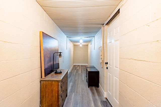 hallway with dark wood-type flooring and concrete block wall