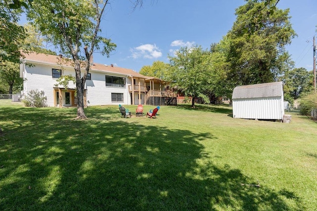 view of yard featuring a deck, an outdoor structure, fence, and a shed