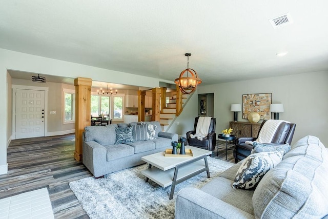 living room with visible vents, dark wood-type flooring, a chandelier, baseboards, and stairs