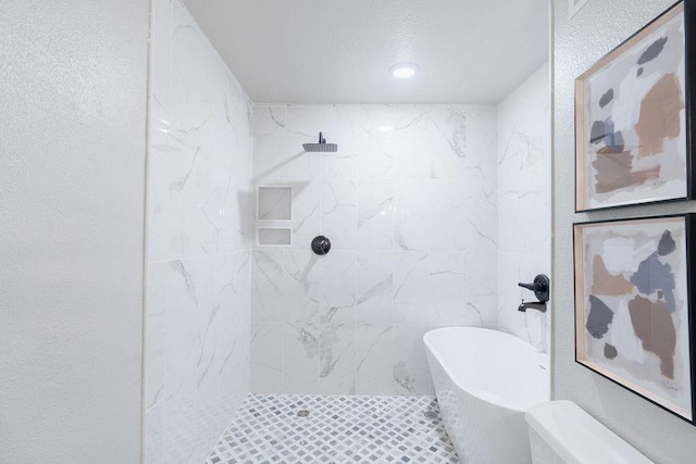 bathroom featuring a soaking tub, a walk in shower, and a textured wall