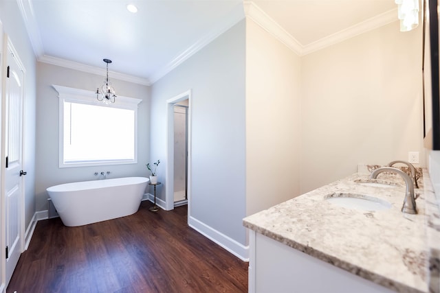 bathroom featuring a bath, a chandelier, hardwood / wood-style floors, ornamental molding, and vanity