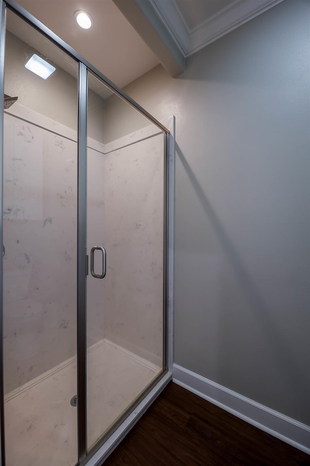 bathroom with crown molding, hardwood / wood-style flooring, and a shower with shower door