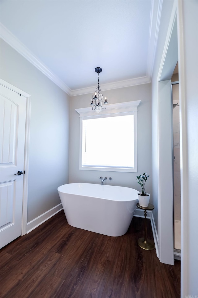 bathroom with a tub to relax in, ornamental molding, hardwood / wood-style flooring, and a chandelier