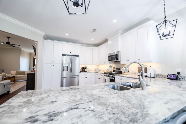 kitchen featuring appliances with stainless steel finishes, light stone countertops, decorative light fixtures, sink, and white cabinetry