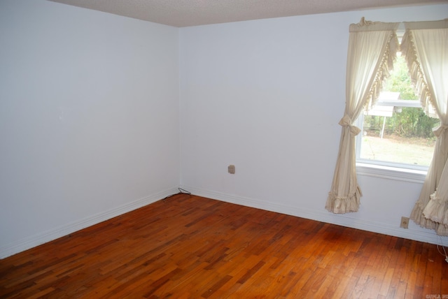 empty room featuring a textured ceiling and dark hardwood / wood-style floors