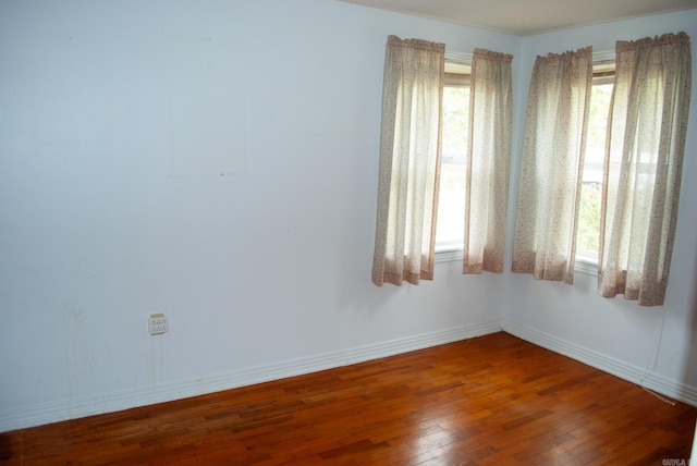 spare room featuring hardwood / wood-style flooring and baseboards