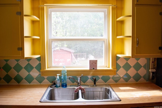 kitchen with light countertops, a sink, open shelves, and backsplash
