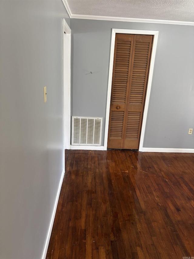 unfurnished bedroom featuring crown molding, wood-type flooring, baseboards, visible vents, and a closet