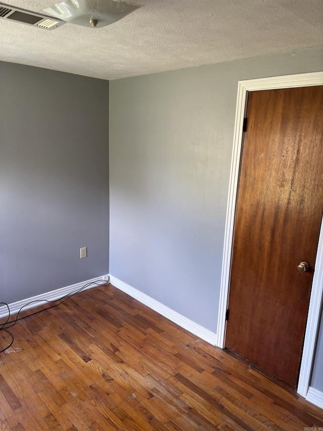 empty room with dark wood-style flooring, baseboards, and a textured ceiling
