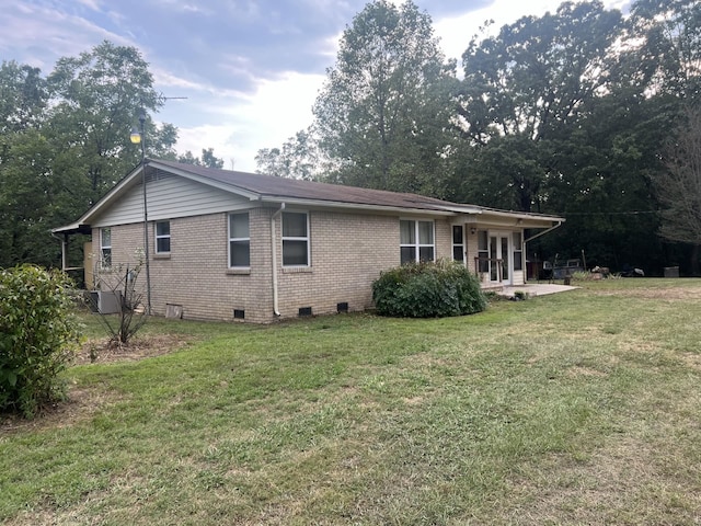 back of property featuring crawl space, a yard, and brick siding