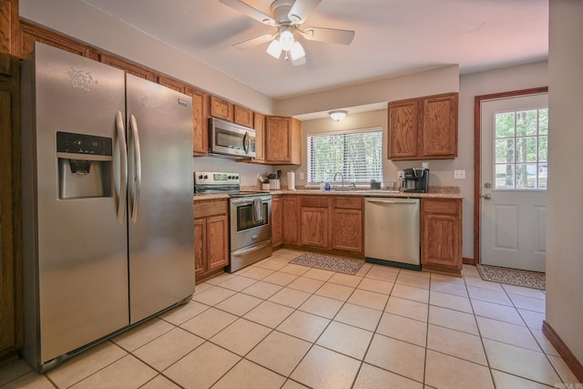 kitchen with appliances with stainless steel finishes, plenty of natural light, ceiling fan, and light tile patterned flooring