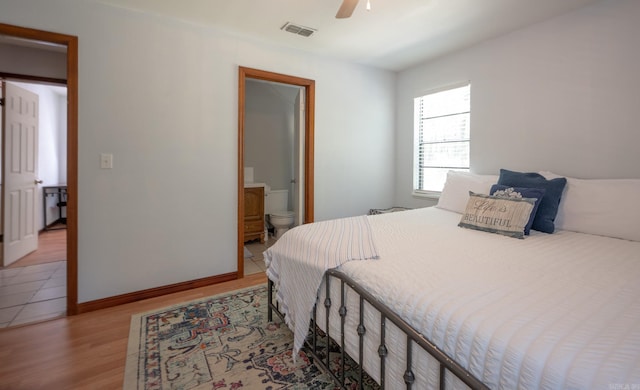 bedroom featuring light hardwood / wood-style floors, ceiling fan, and ensuite bath