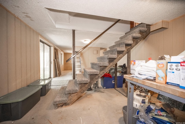 basement featuring a textured ceiling and wooden walls