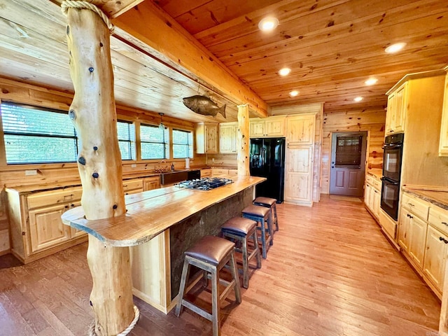 kitchen featuring black appliances, light wood-type flooring, wooden walls, a kitchen island, and wood ceiling