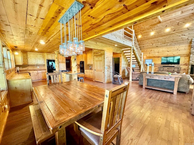 dining area with sink, light hardwood / wood-style flooring, a chandelier, wooden ceiling, and wooden walls