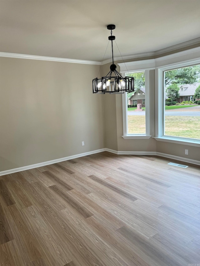 empty room featuring wood-type flooring, an inviting chandelier, and ornamental molding