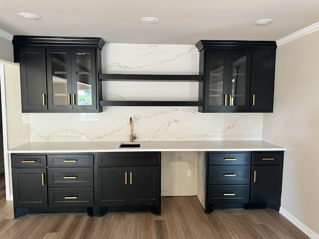 bar featuring backsplash, wood-type flooring, ornamental molding, and sink