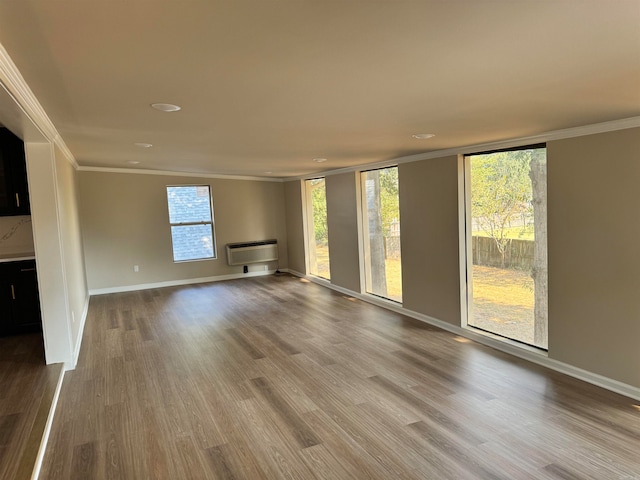 unfurnished living room featuring ornamental molding, an AC wall unit, and hardwood / wood-style floors