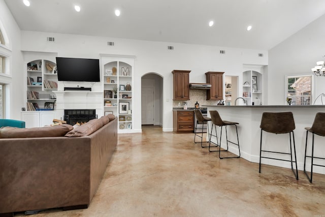 living room featuring built in features, an inviting chandelier, and sink