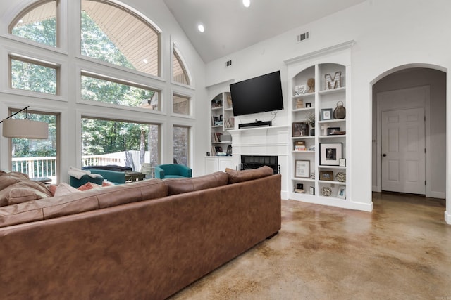 living room featuring high vaulted ceiling, a tiled fireplace, plenty of natural light, and built in features