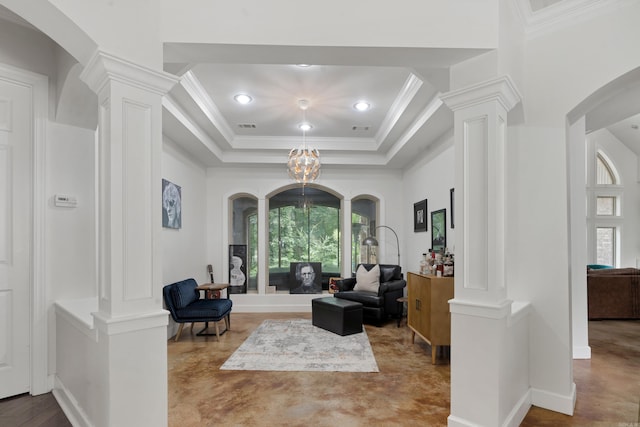 living room featuring crown molding, decorative columns, a notable chandelier, and a tray ceiling