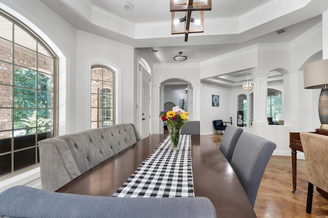 dining room featuring crown molding, a tray ceiling, and ornate columns