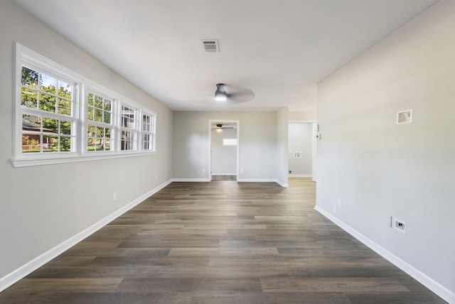 unfurnished room with a ceiling fan, dark wood finished floors, visible vents, and baseboards