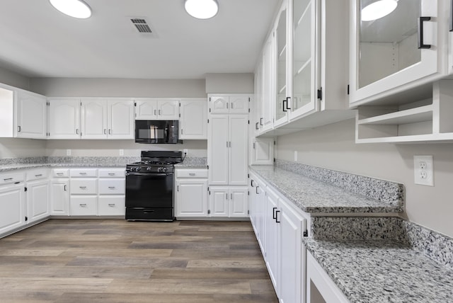 kitchen featuring light stone countertops, black appliances, white cabinetry, and wood finished floors