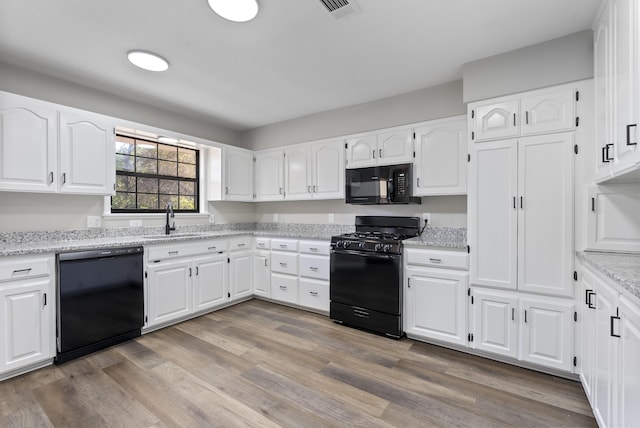 kitchen featuring black appliances, a sink, white cabinetry, and light wood-style floors