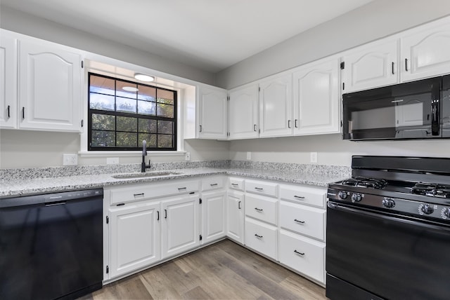 kitchen featuring white cabinetry, a sink, light wood-style flooring, and black appliances