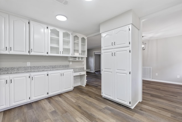 kitchen featuring light stone countertops, visible vents, glass insert cabinets, and white cabinets