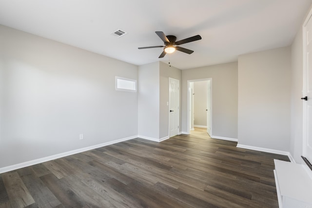 empty room featuring dark wood-style floors, visible vents, and baseboards