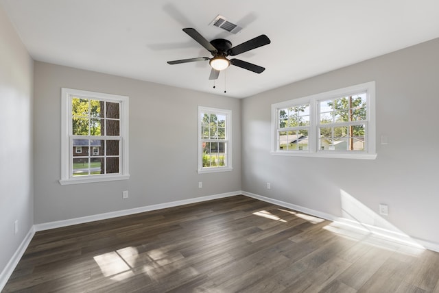 spare room featuring ceiling fan, baseboards, visible vents, and dark wood finished floors