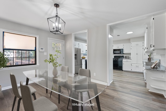 dining space featuring baseboards, an inviting chandelier, and light wood-style floors