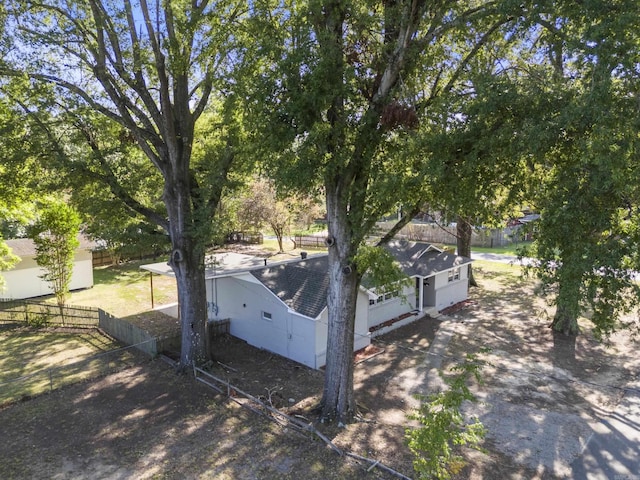 view of side of property featuring fence private yard and roof with shingles