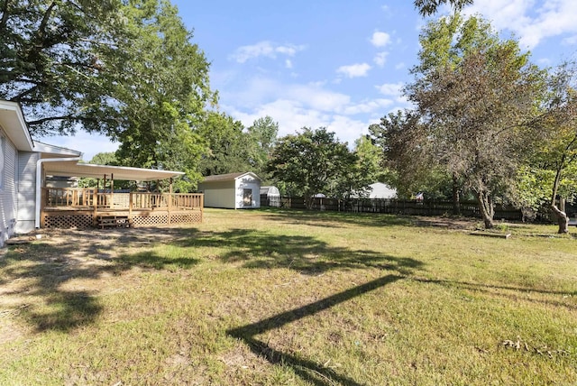 view of yard with a storage shed, a fenced backyard, an outdoor structure, and a wooden deck