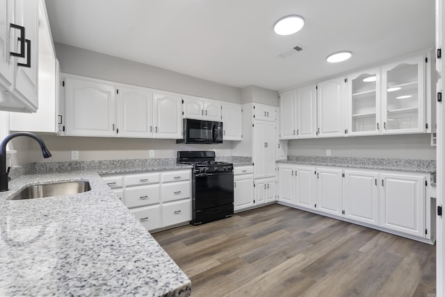 kitchen with visible vents, glass insert cabinets, black appliances, white cabinetry, and a sink