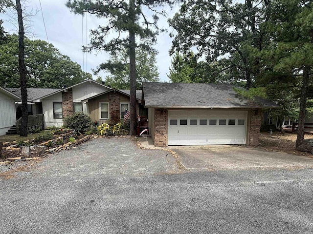 single story home featuring a garage, brick siding, driveway, and a shingled roof