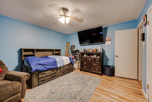 bedroom featuring a ceiling fan, a textured ceiling, and light wood finished floors