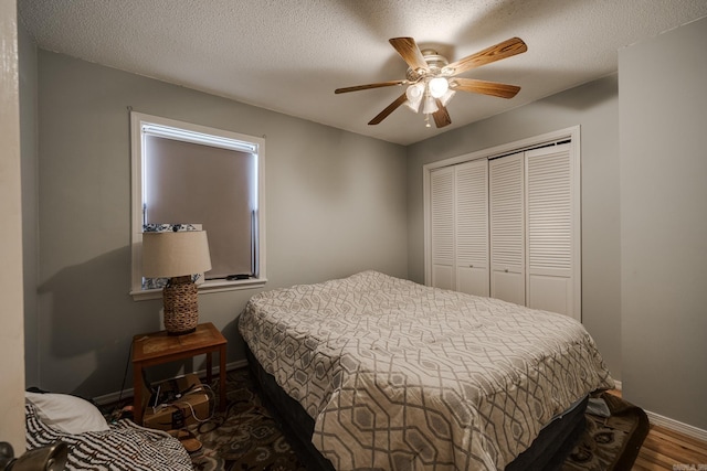 bedroom featuring a closet, a ceiling fan, a textured ceiling, wood finished floors, and baseboards