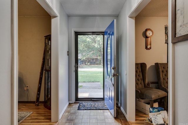 entryway with a textured ceiling, baseboards, and wood finished floors