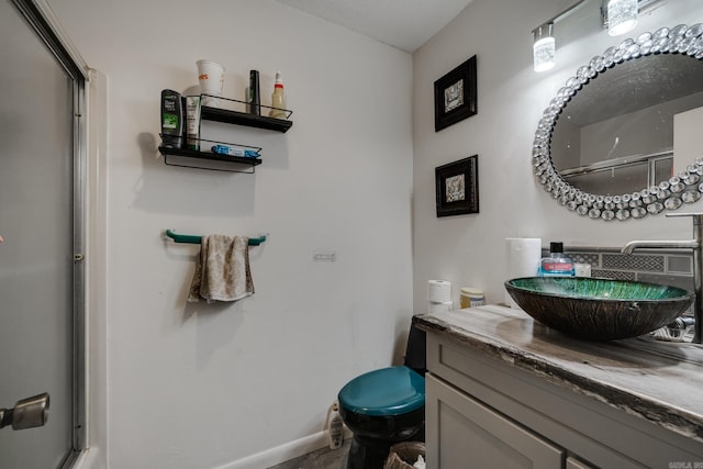 bathroom with a shower with shower door, vanity, and baseboards