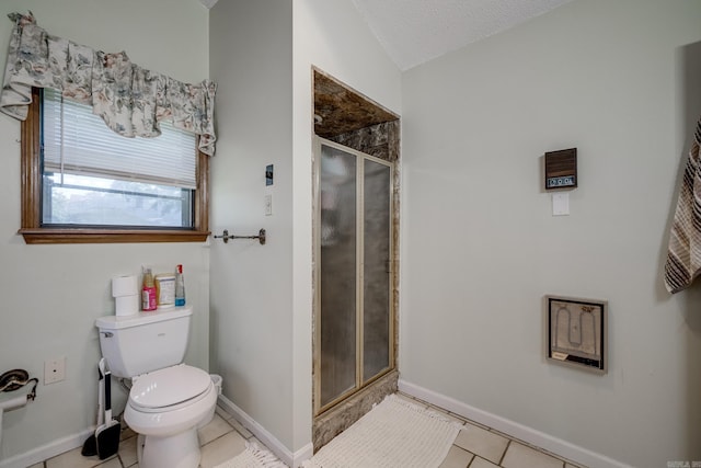 full bath featuring toilet, a stall shower, baseboards, and tile patterned floors