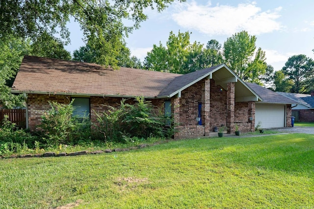 view of front of home featuring an attached garage, driveway, a front lawn, and brick siding