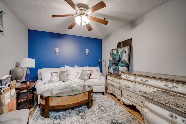 bedroom with a textured ceiling, light wood finished floors, visible vents, and a ceiling fan